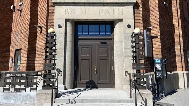 Un bâtiment doté d’une entrée à double porte, d’un escalier et d’un banc.