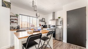 Une cuisine moderne avec un îlot central en bois, des appareils en acier inoxydable et une porte noire.