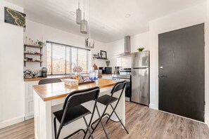 Eine moderne Küche mit einer Holztheke, Edelstahlgeräten und einer schwarzen Tür.