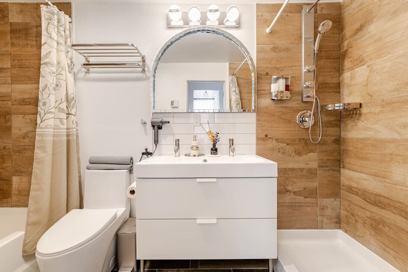 A bathroom with a white sink, mirror, and shower.