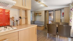 A compact kitchenette with a stove, a small sink, and a cabinet. There is a dining area with a table and chairs, and a sofa.