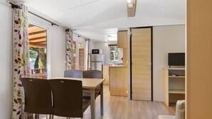 A compact living space with a dining area, kitchenette, and a TV.
