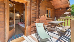 A wooden cabin with a balcony, a ladder, a bed, and a table. - Apartment 'Lys blanc' with Mountain View, Wi-Fi and Air Conditioning (Vaulnaveys-le-Bas)