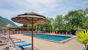 A poolside area with lounge chairs, a swimming pool, and thatched umbrellas. - Apartment 'Lys blanc' with Mountain View, Wi-Fi and Air Conditioning (Vaulnaveys-le-Bas)