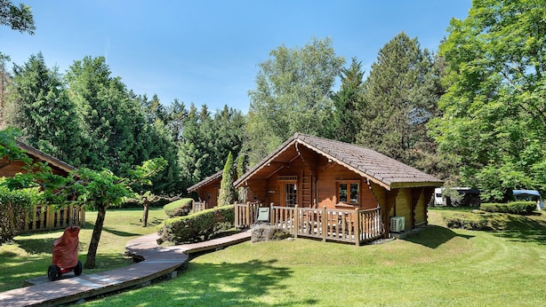 A wooden cabin with a porch, surrounded by a well-maintained lawn and trees. - Apartment 'Lys blanc' with Mountain View, Wi-Fi and Air Conditioning (Vaulnaveys-le-Bas)