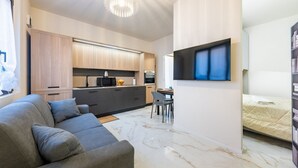 Un espacio habitable moderno con sofá, zona de comedor, cocina y cama.