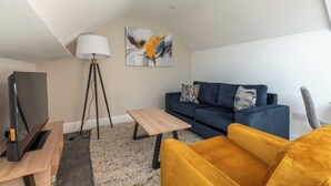 A living room with a sofa, a coffee table, a TV, and a lamp. - Old Dutch Embassy by Guestz (Hull)