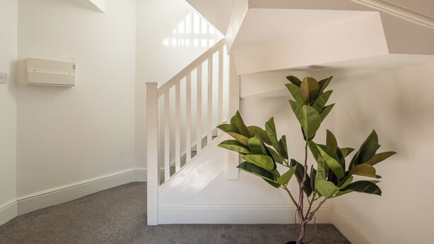 A staircase with white railings, a grey carpeted floor, and a potted plant. - Old Dutch Embassy by Guestz (Hull)