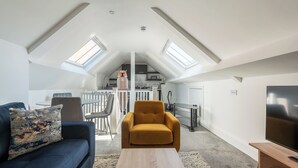 A loft-style living space with a sofa, armchair, and a TV. - Old Dutch Embassy by Guestz (Hull)