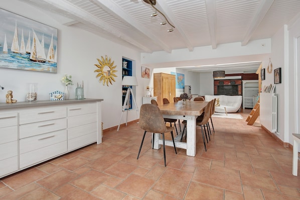 Una cocina amplia con comedor, muebles blancos y un ventanal grande.