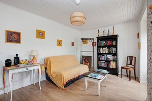 Una sala de estar acogedora con un sofá, una mesa de centro, una estantería y una lámpara.