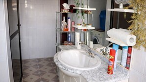 Een badkamer met een witte wastafel, een marmeren aanrechtblad en een spiegel met een zeepdispenser.