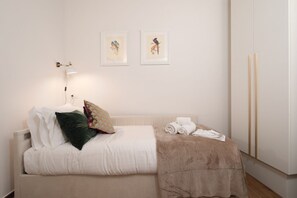 A bedroom with a bed, pillows, a blanket, a bedside table with a lamp, and two framed pictures on the wall. - San Niccolò Atelier Grande (Firenze)