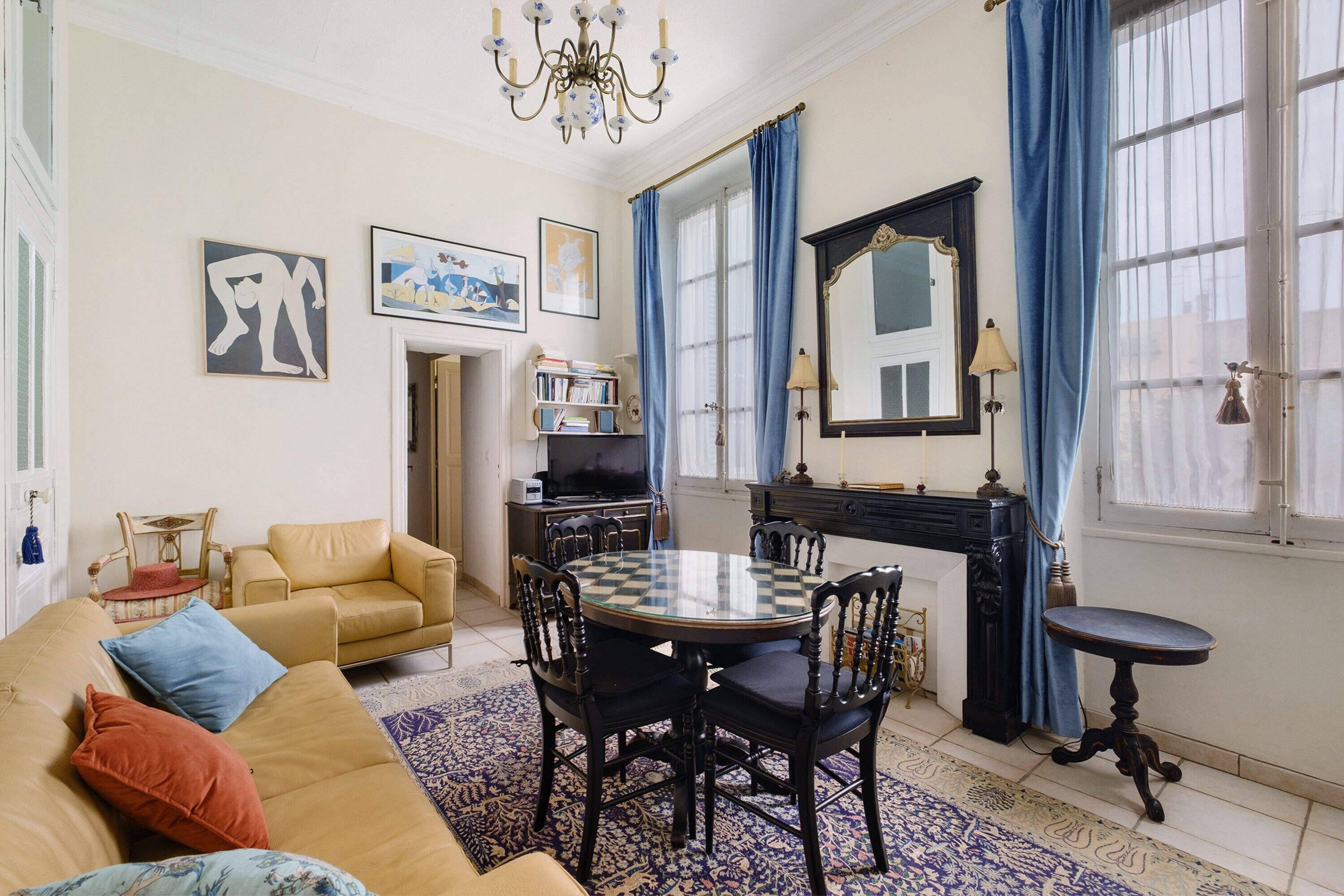 Un salon comprenant un canapé, une table ronde avec des chaises, une cheminée et un grand miroir.