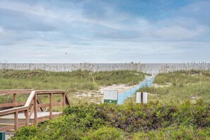 A wooden boardwalk leading to a beach with a sign and a blue pathway. - Spacious 1BR Island Club Steps to Beach (Hilton Head Island)