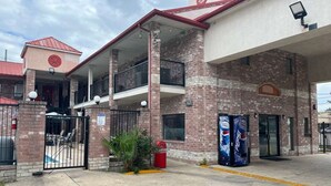 A building with a brick facade, a covered outdoor seating area, and a Pepsi vending machine. - FairBridge Inn near Riverwalk - Alamo (San Antonio)