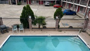 A rectangular swimming pool with a metal ladder, surrounded by a brick wall and a metal fence. - FairBridge Inn near Riverwalk - Alamo (San Antonio)