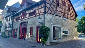 Un bâtiment traditionnel à colombages, avec des murs en pierre, des fenêtres à cadre rouge et une entrée de magasin.