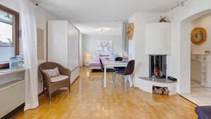 Un intérieur moderne avec un coin repas, une cheminée et une chambre à coucher à l’arrière-plan.