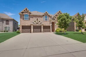 A two-story house with a garage, brick exterior, and a well-maintained lawn. - The Full Package (Grand Prairie)