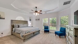 Un dormitorio con cama, una silla, cómoda y ventilador de techo.