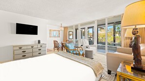 Ein Hotelzimmer mit einem Bett, einem Schreibtisch, einem Sessel, einem Sofa, einem Fernseher und einem großen Fenster.