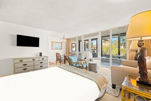 Ein Hotelzimmer mit einem Bett, einem Schreibtisch, einem Sessel, einem Sofa, einem Fernseher und einem großen Fenster.
