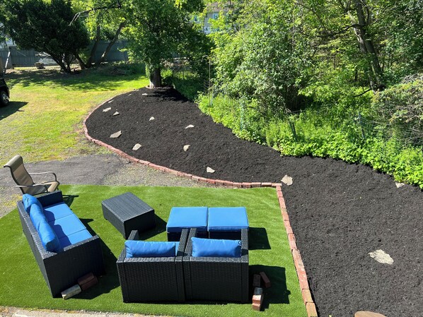 Een tuin met een kronkelend pad, tuinmeubilair en een bakstenen rand.