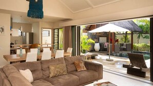 Ein modernes Wohnzimmer mit einer Couch, einem Essbereich und Blick auf einen Poolbereich im Freien.