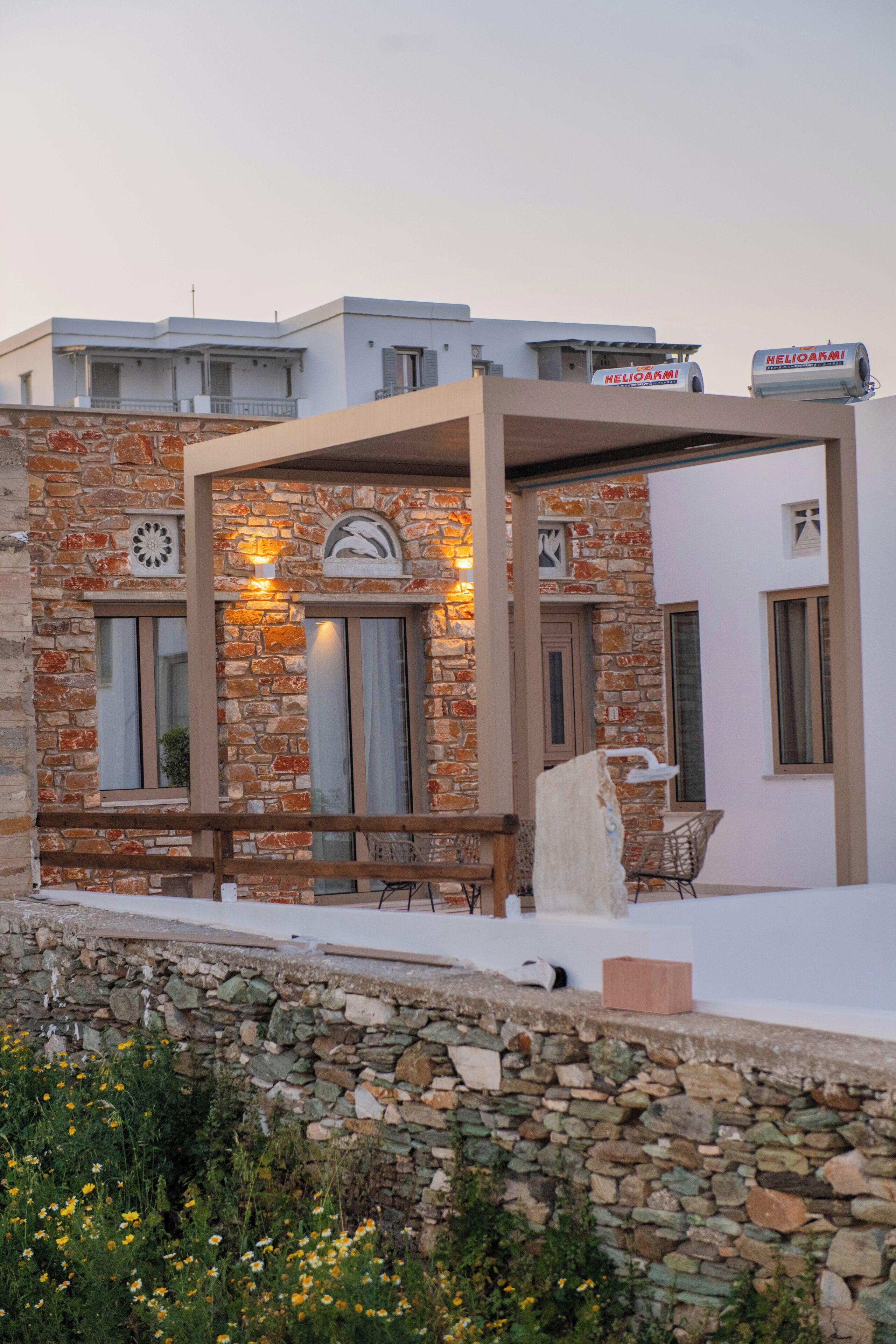 Un edificio con fachada de piedra, varias ventanas y un área de estar al aire libre techada.