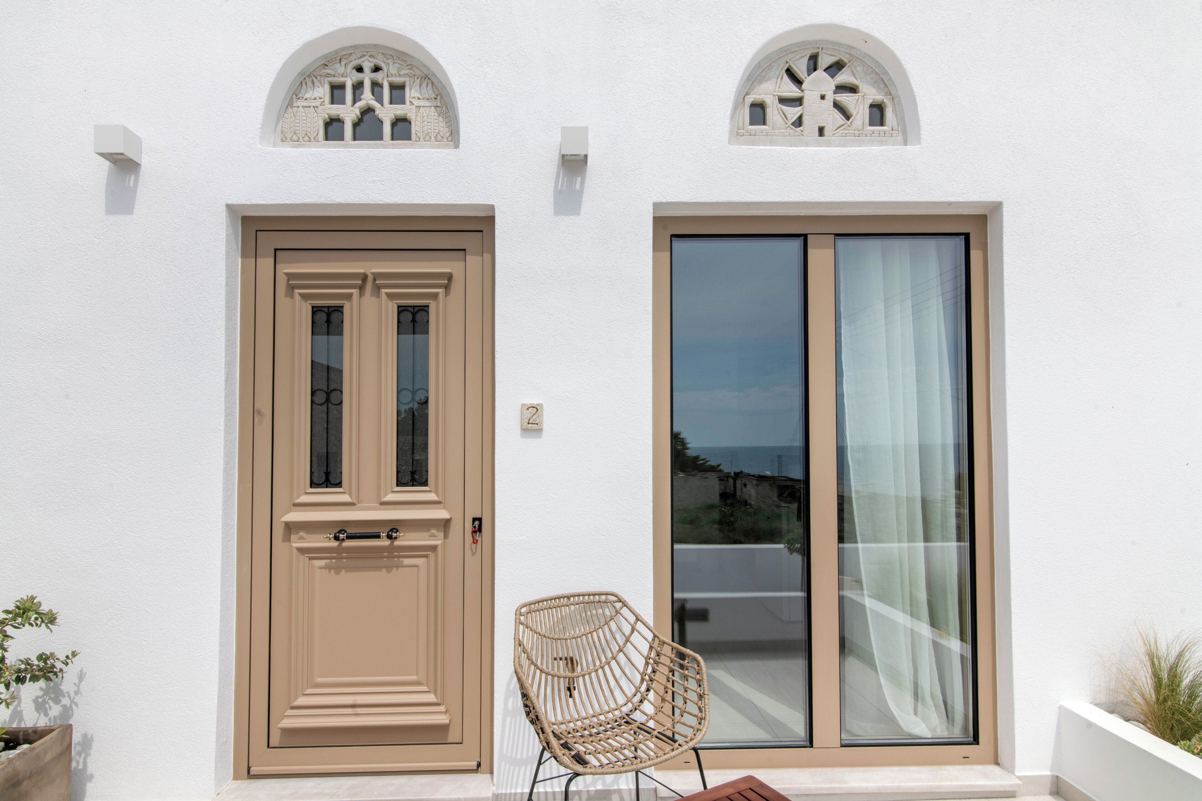 A building with a beige door, a large glass sliding door, and a wicker chair outside.