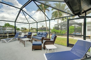 Un espacio al aire libre con techo, amueblado con mobiliario de mimbre y sillones reclinables.
