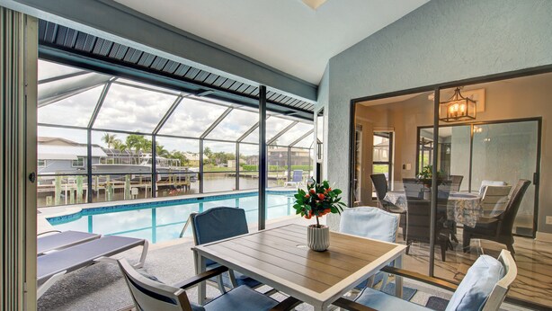 Ein Poolbereich mit Tisch und Stühlen, einem Blumentopf und Blick auf den Pool.