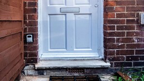 Una puerta blanca con el número 27, un pequeño ventanal arriba y una ranura para correo a la izquierda.