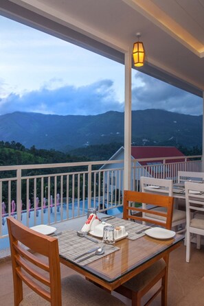 A dining area with a table set for two, overlooking a mountainous landscape.