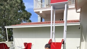 A child on a red slide in a backyard with artificial grass, white walls, and a red roof. - The Fog Munnar Resorts And Spa (Devikolam)