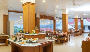 A spacious dining area with high ceilings, wooden pillars, and large windows offering a view of the landscape.