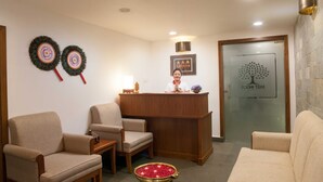 A reception area with a wooden desk, two chairs, a Buddha statue, and a Bodhi Tree sign on the door. - The Fog Munnar Resorts And Spa (Devikolam)