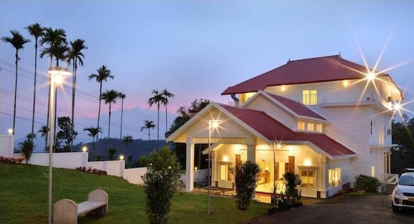 A two-story house with a red roof, a porch, and a driveway.