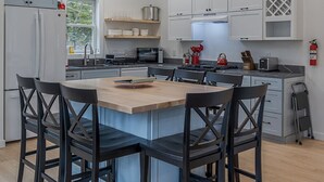 Une cuisine moderne dotée d’un îlot central, de meubles blancs et d’un coin repas avec des chaises noires.