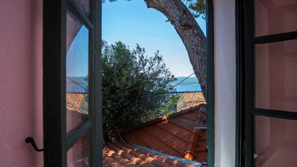 A view through a window with a tiled roof and a tree outside. - Charming Holiday Apartment in the Heart of Postup Vineyards – Spectacular Sea Views! (Orebić)