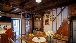 A rustic wooden dining table with a lace doily, a vase with flowers, and a basket of fruit. - Charming Holiday Apartment in the Heart of Postup Vineyards – Spectacular Sea Views! (Orebić)
