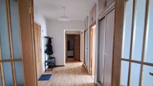 Ein Flur mit Holzboden, Schiebetüren und einer Deckenleuchte.