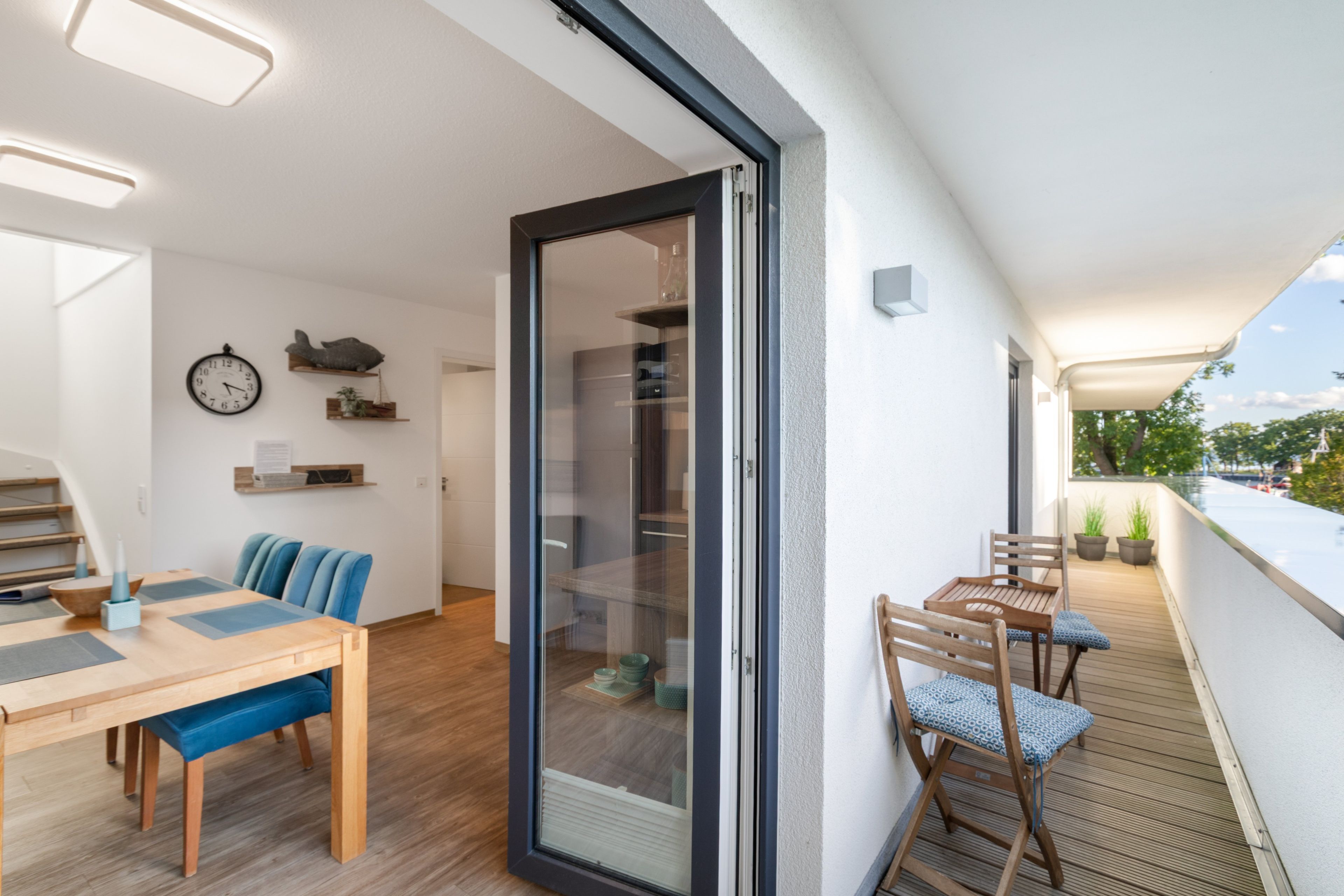 A modern interior with a dining area, a sofa, a table, and a balcony with chairs.