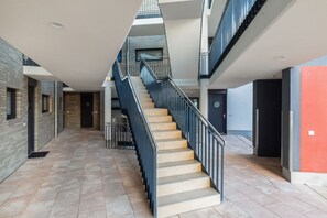 A multi-level interior with a central staircase, tiled flooring, and a mix of brick and smooth wall finishes. - Enjoy Sea Views & Tranquility – Exclusive Penthouse Apartment in Lauterbach Harbor (Putbus)