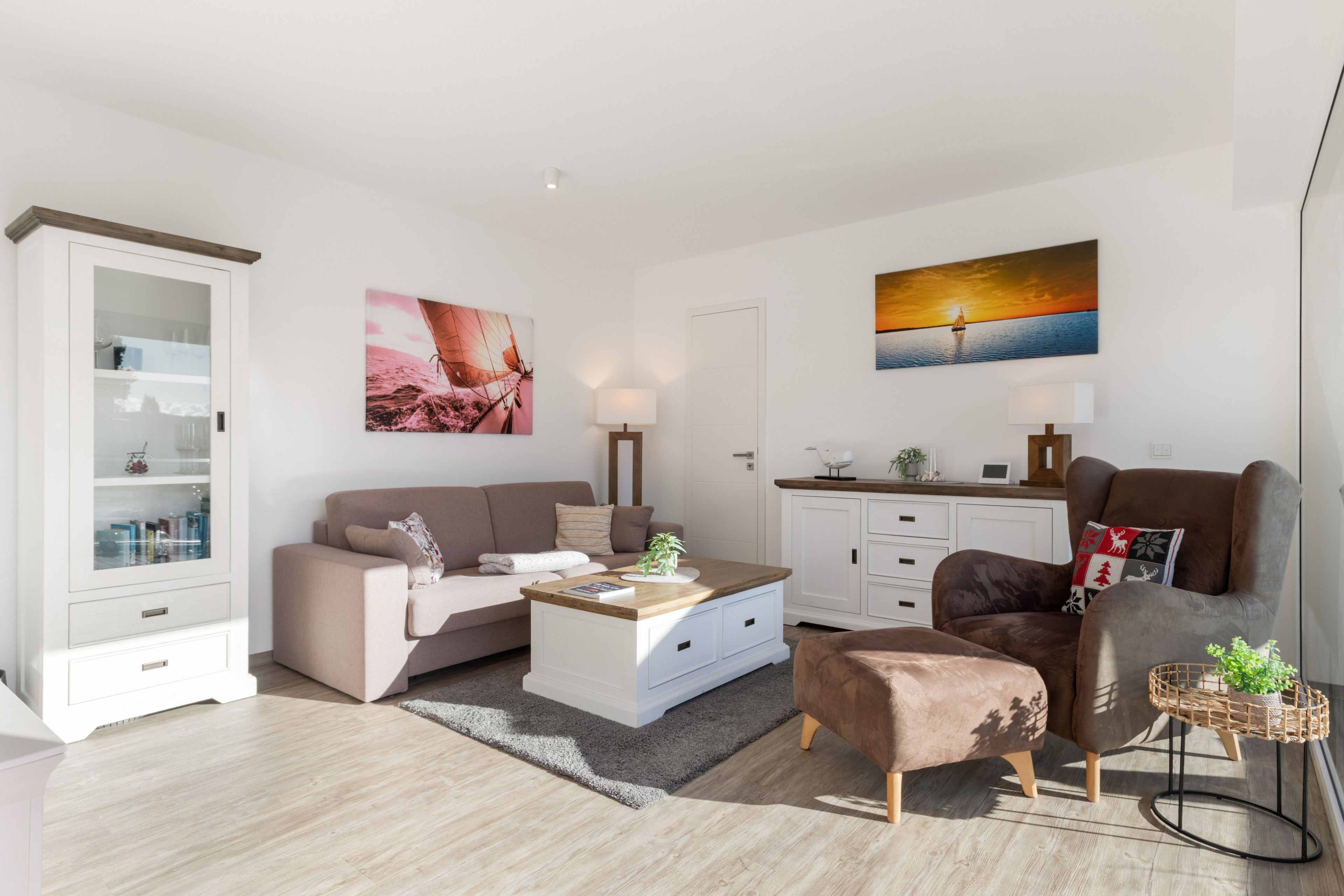 A modern living room with a sofa, coffee table, and a decorative chair. There is a cabinet with glass doors and a painting on the wall.