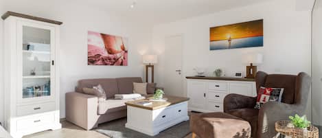 A modern living room with a sofa, coffee table, and a decorative chair. There is a cabinet with glass doors and a painting on the wall.