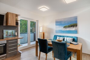 A modern kitchen with a built-in oven and a dining area with a table and chairs. - Enjoy Sea Views & Tranquility – Exclusive Penthouse Apartment in Lauterbach Harbor (Putbus)