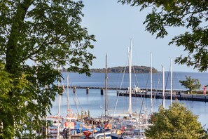 A marina with boats docked, a pier extending into the water, and a distant island. - Enjoy Sea Views & Tranquility – Exclusive Penthouse Apartment in Lauterbach Harbor (Putbus)