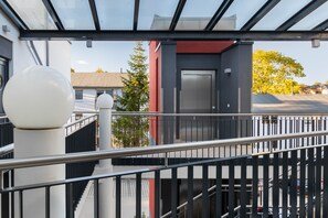 A modern building with a glass facade, a metal railing, and a staircase leading to an elevator. - Enjoy Sea Views & Tranquility – Exclusive Penthouse Apartment in Lauterbach Harbor (Putbus)